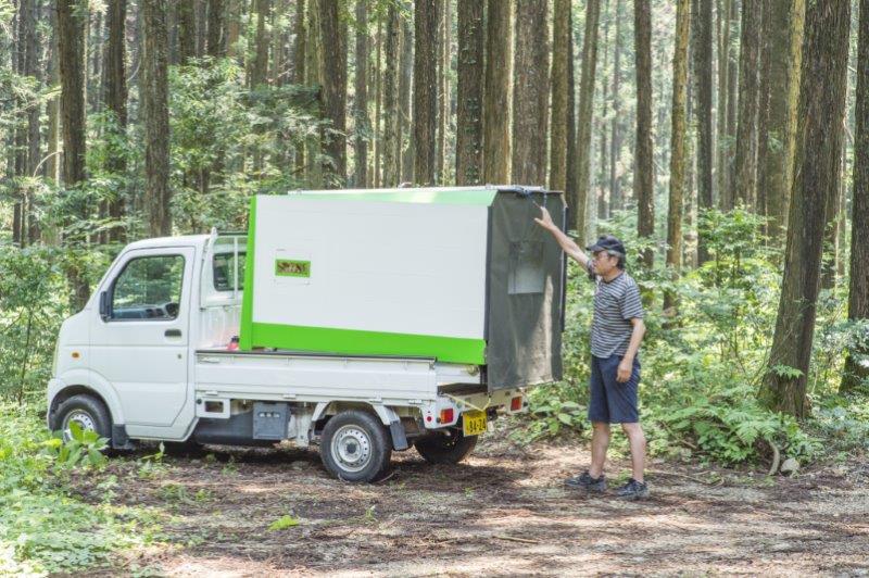 軽トラキャンピングカーの荷台の居住部を拡張するべく、男性が荷台に載せた箱の上部にあるロープに手を掛けている