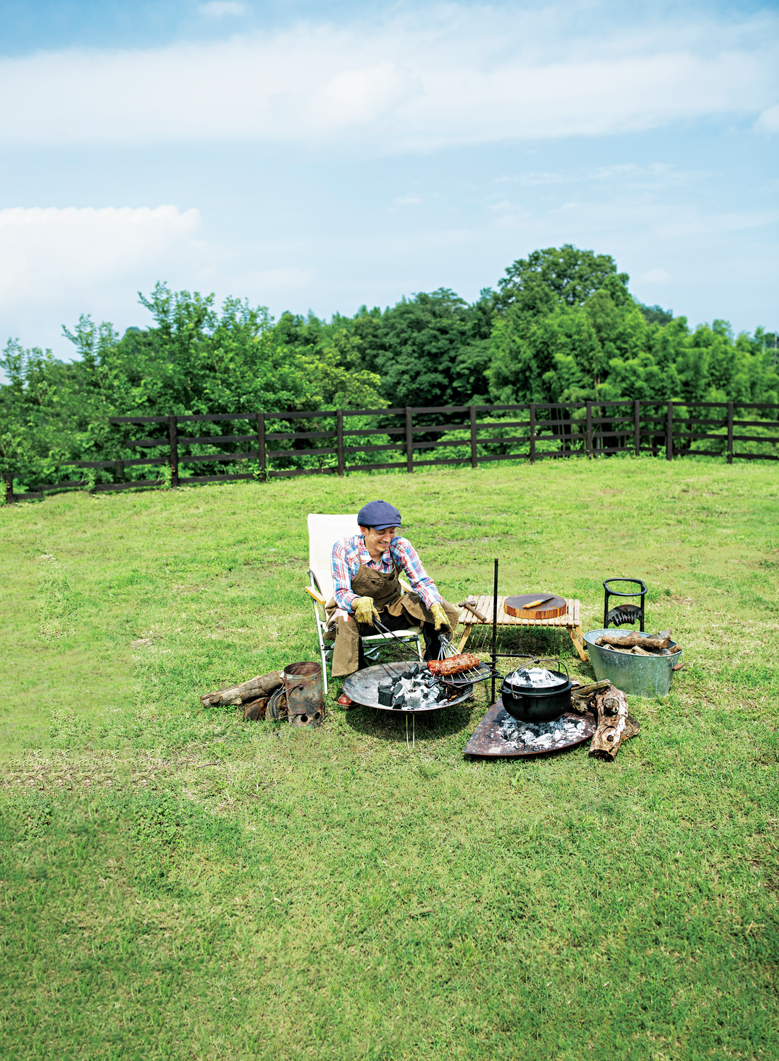 草原で焚き火の傍らに座りケバブを料理する人