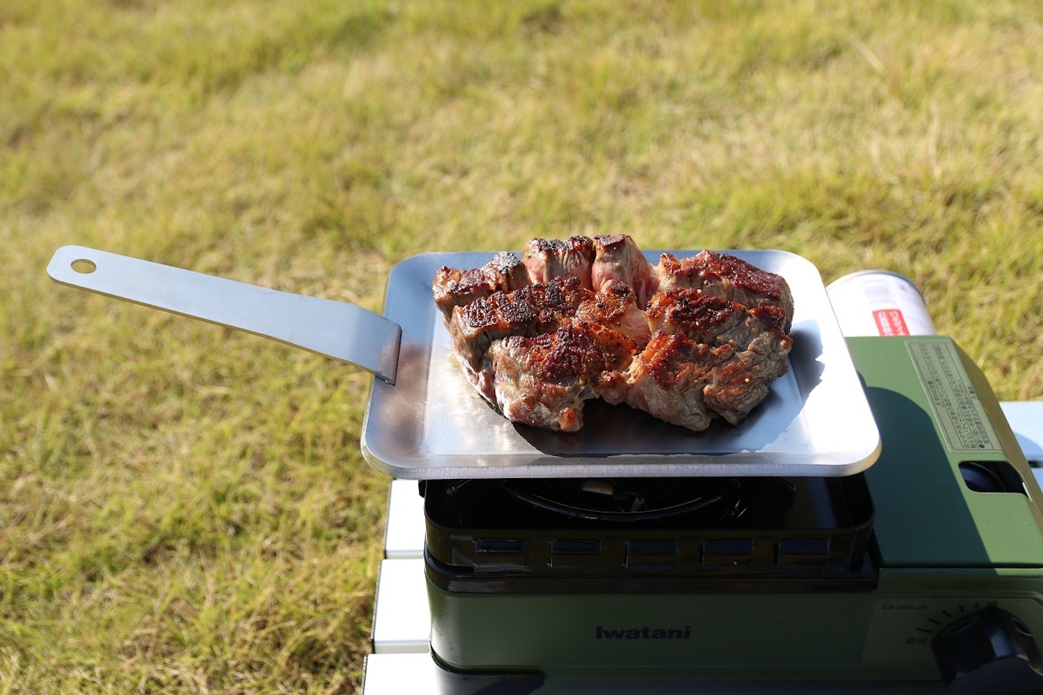 カセットコンロの上に鉄板を置きステーキを焼く