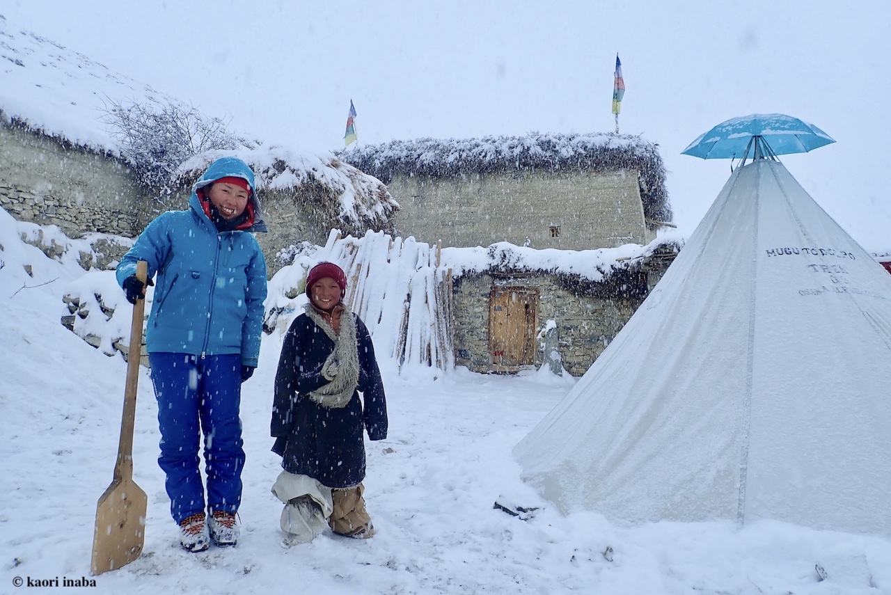 雪かきをする稲葉香さんとチベット仏教の少年僧。ティピー型テント