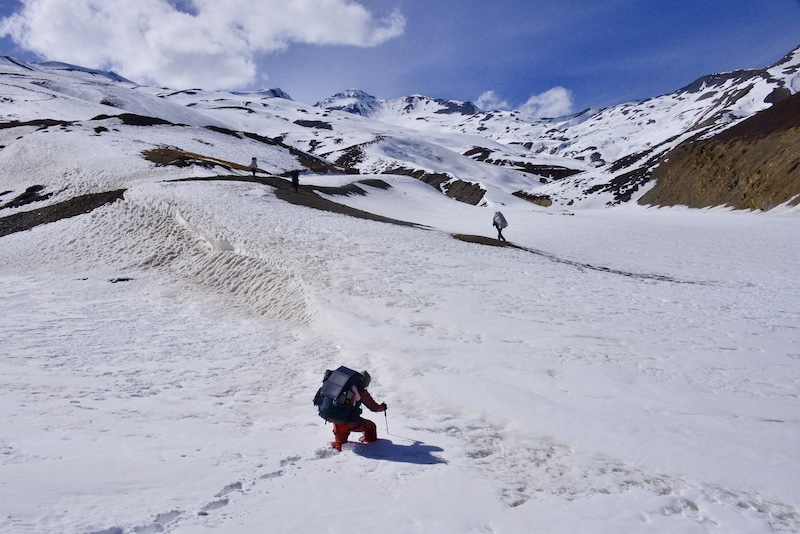 広大な雪の山景色の中、下山するふたりの人物