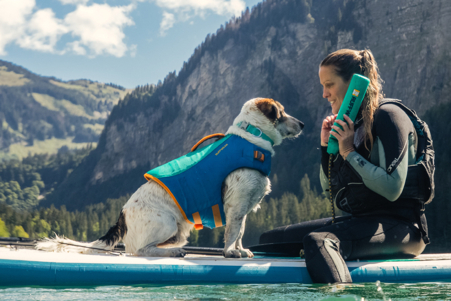 SUPの上に座る女性とラフウェアを着用した犬