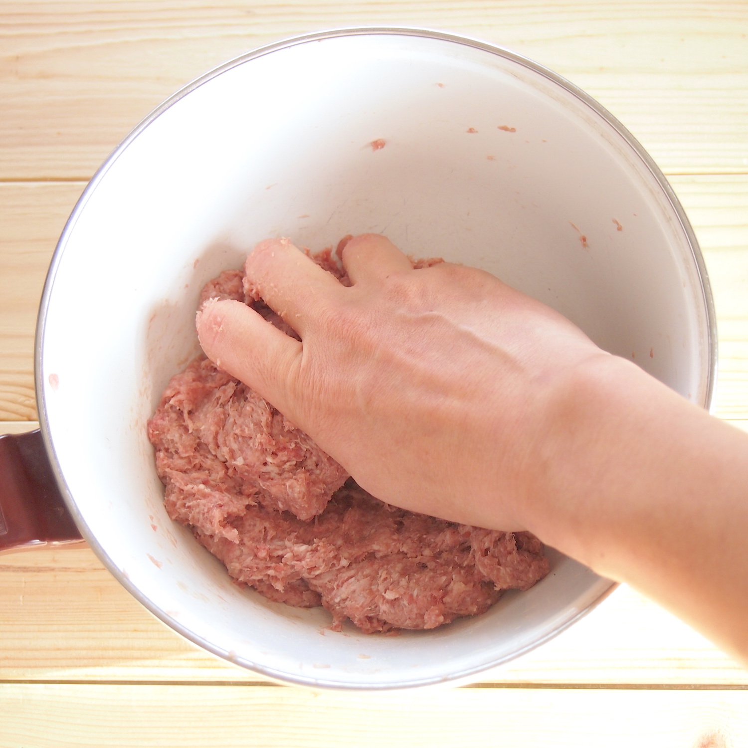 鍋に入れたひき肉を手でこねる