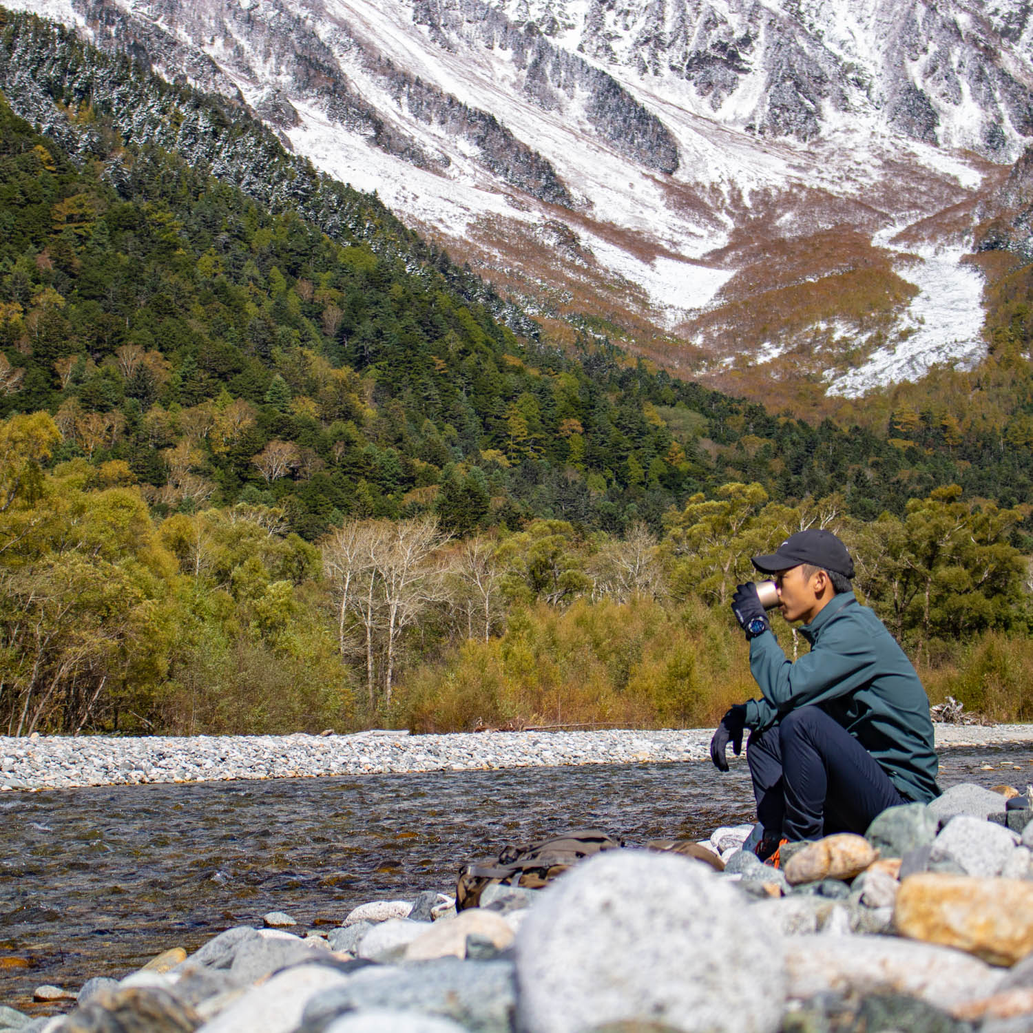 男性が山の景色を見ながらコーヒーを飲んでいる。