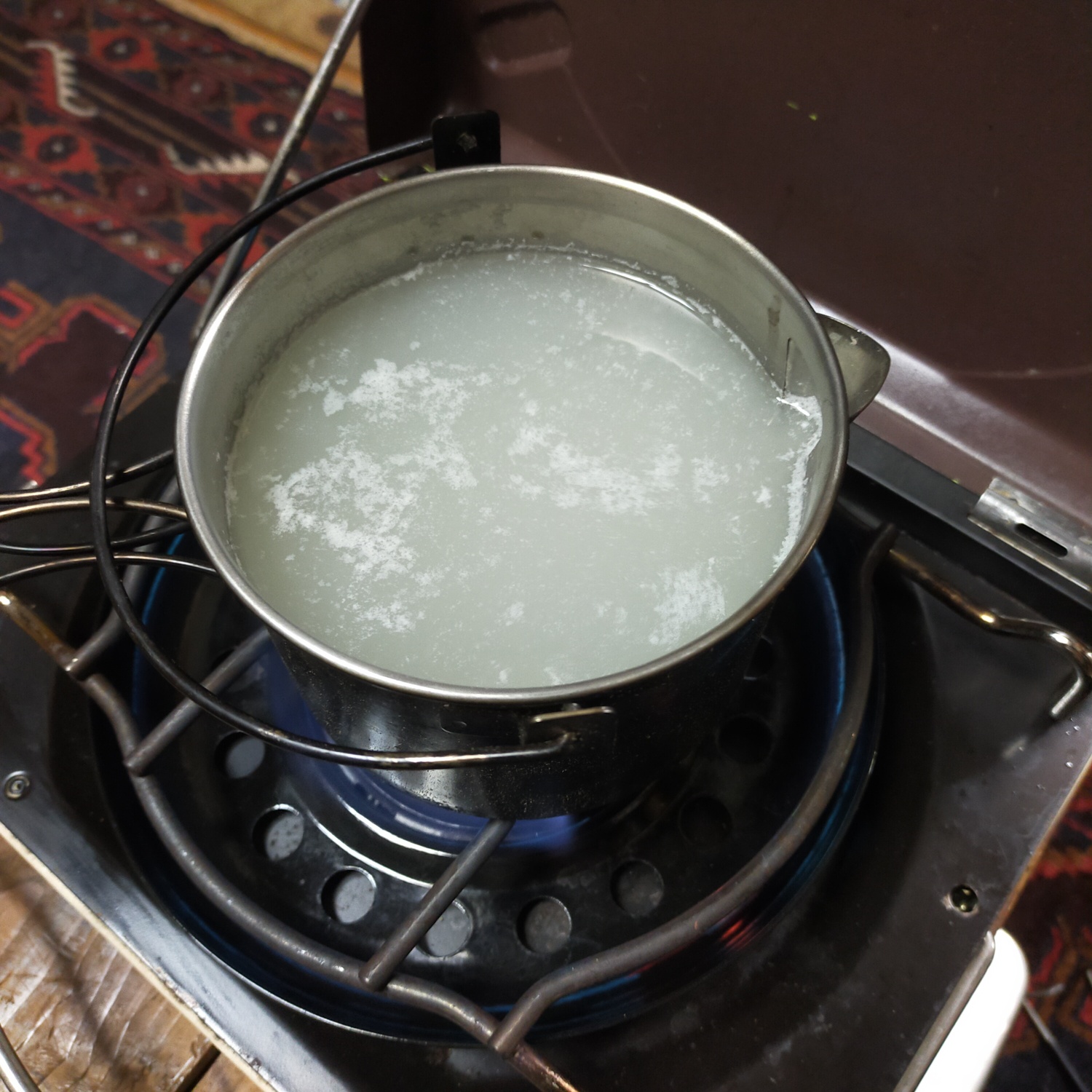 ステンレス製のクッカーに米のとぎ汁を入れて煮ている。