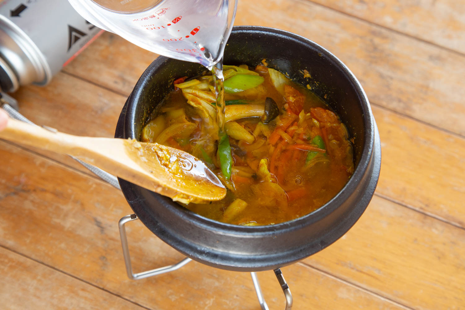 野菜を炒めた土鍋に水を注ぐ様子。