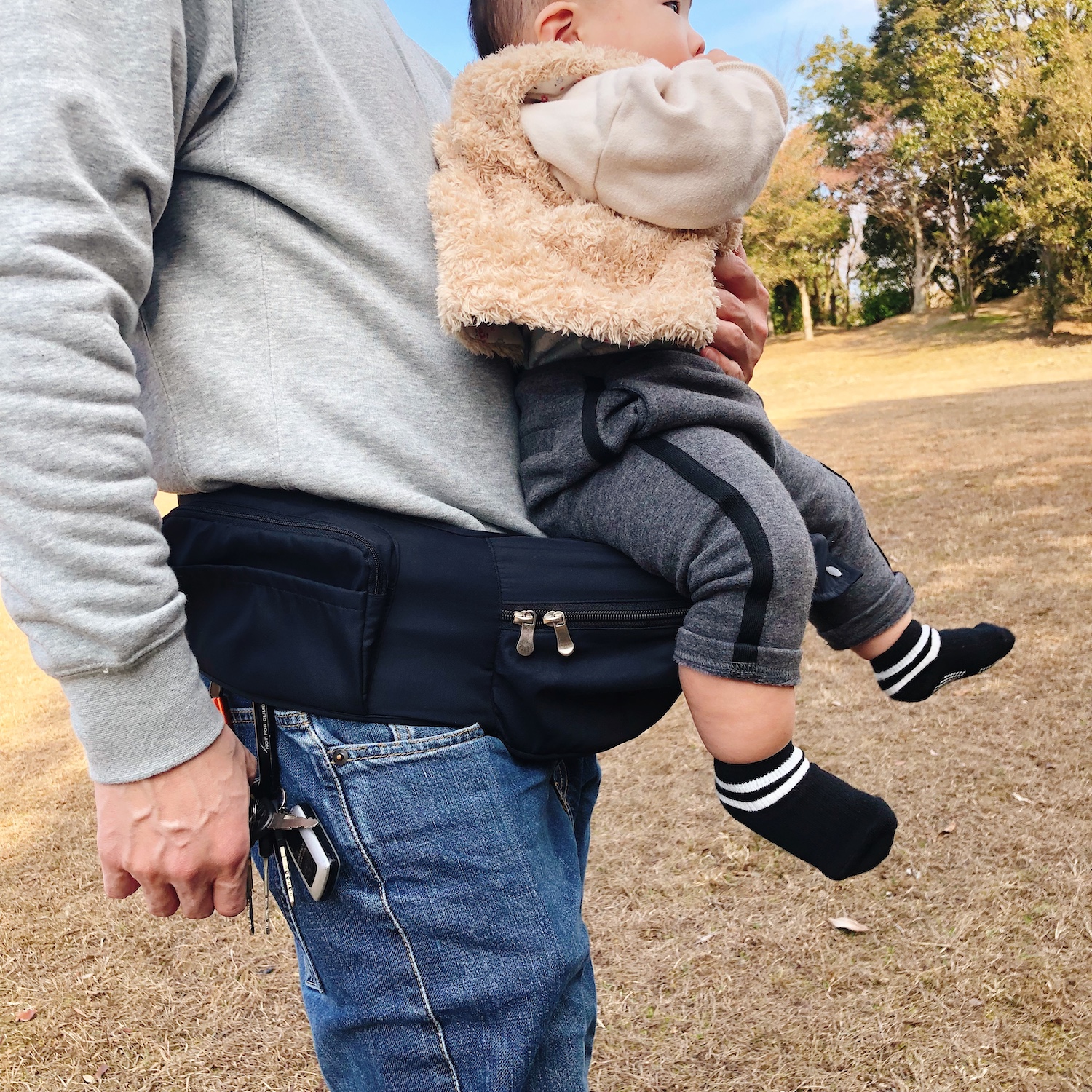 お父さんが素着したヒップシートに座る赤ちゃん