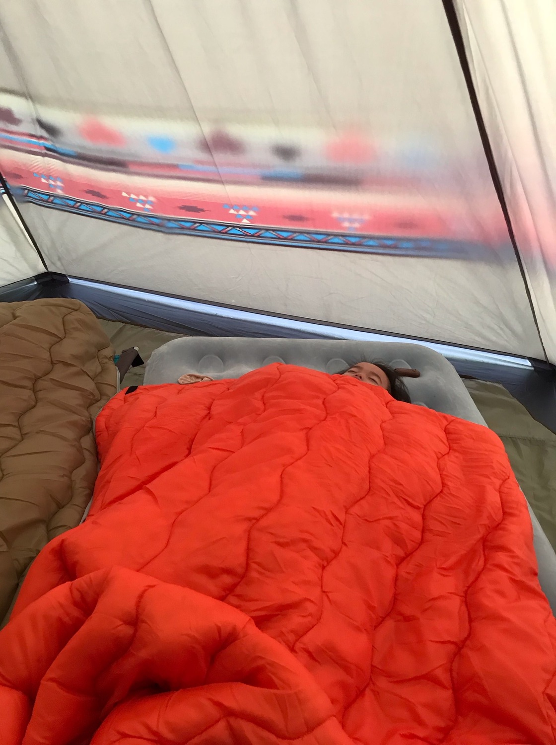 テントの中で眠る3歳の娘。エアベットの上でオレンジ色の寝袋にくるまっている。