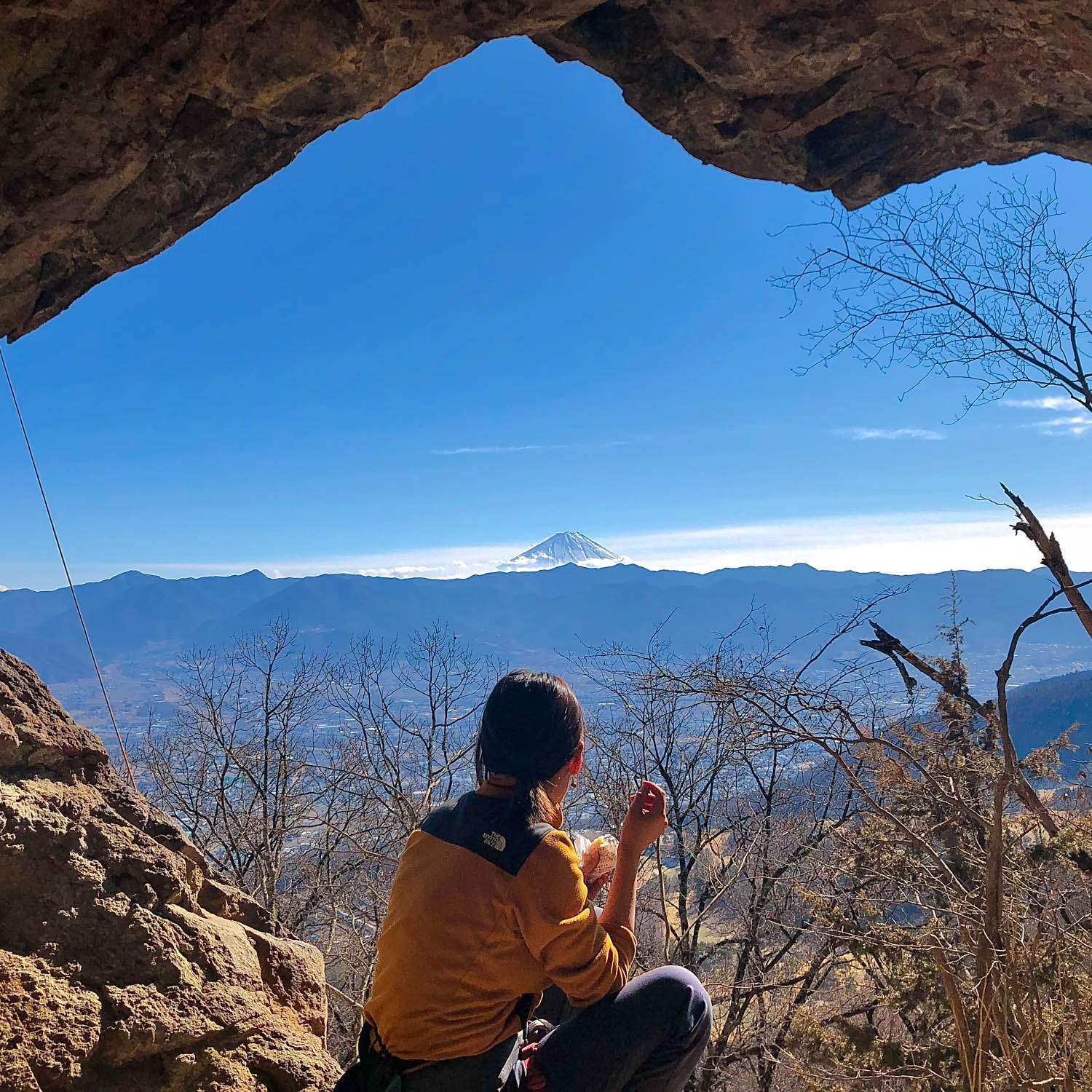 女性が洞窟の中から富士山を眺めている。