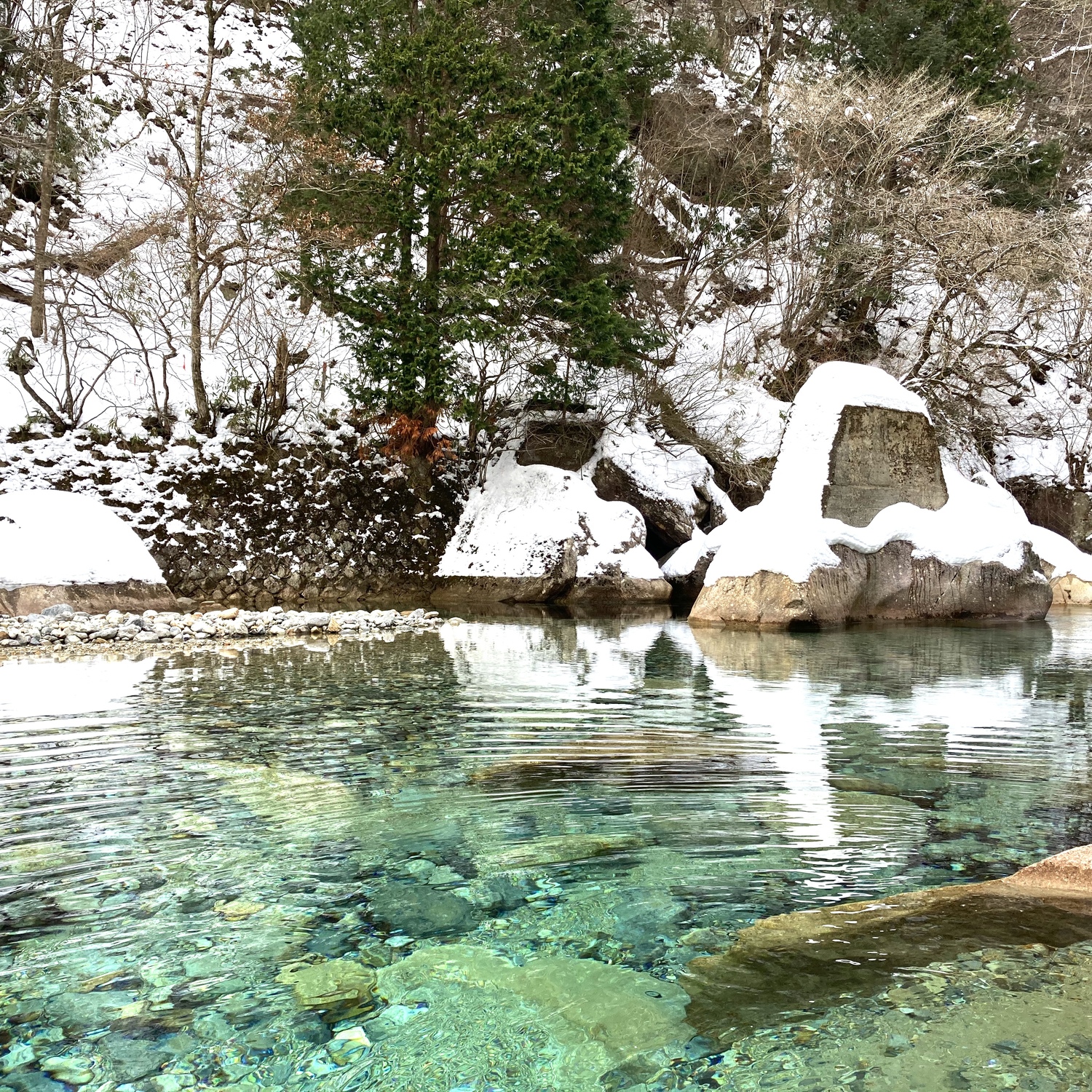 雪の積もった岩と湖の写真が白飛びしている。