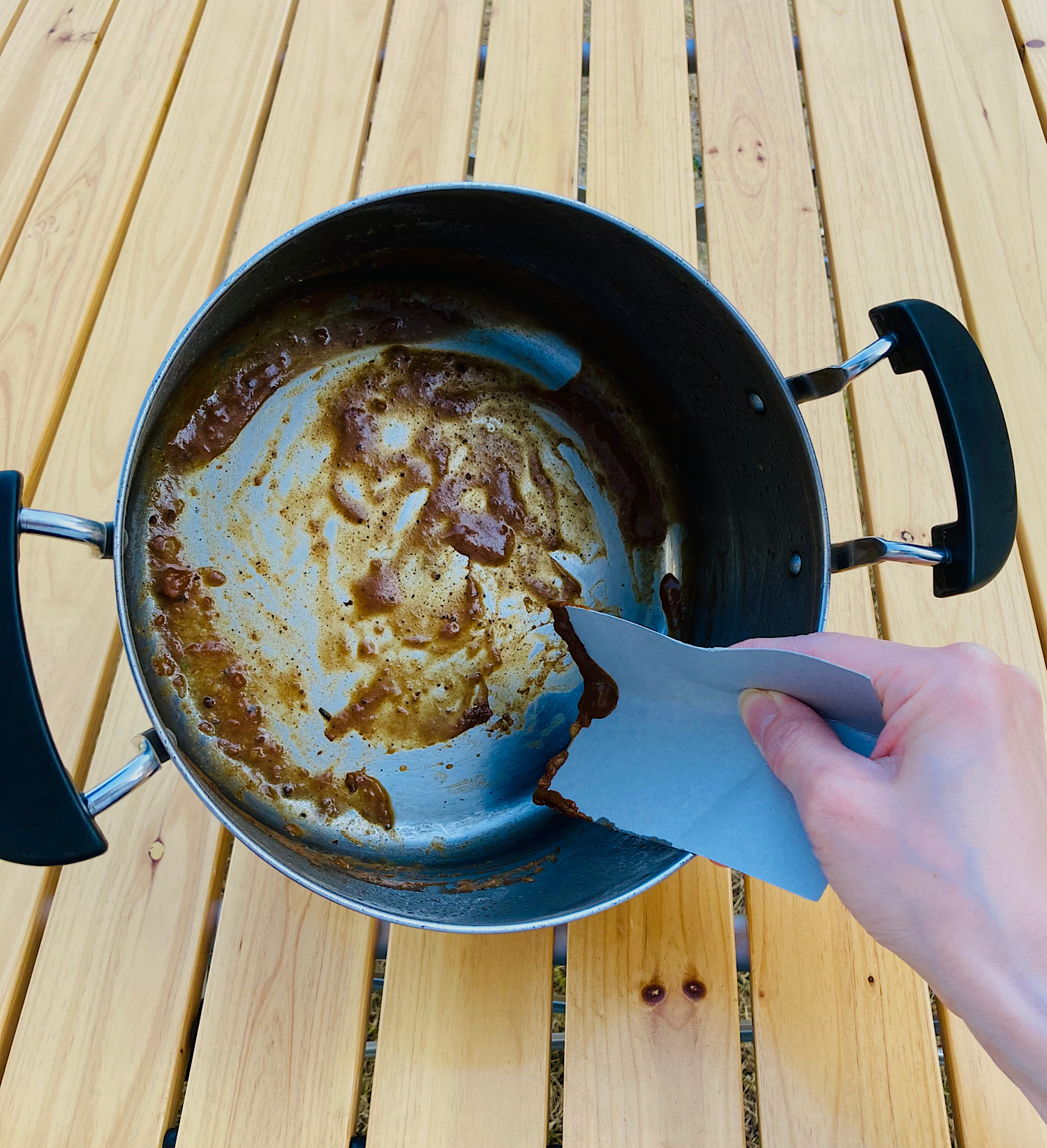 カレー鍋の汚れを厚紙でこそげ取っている様子。