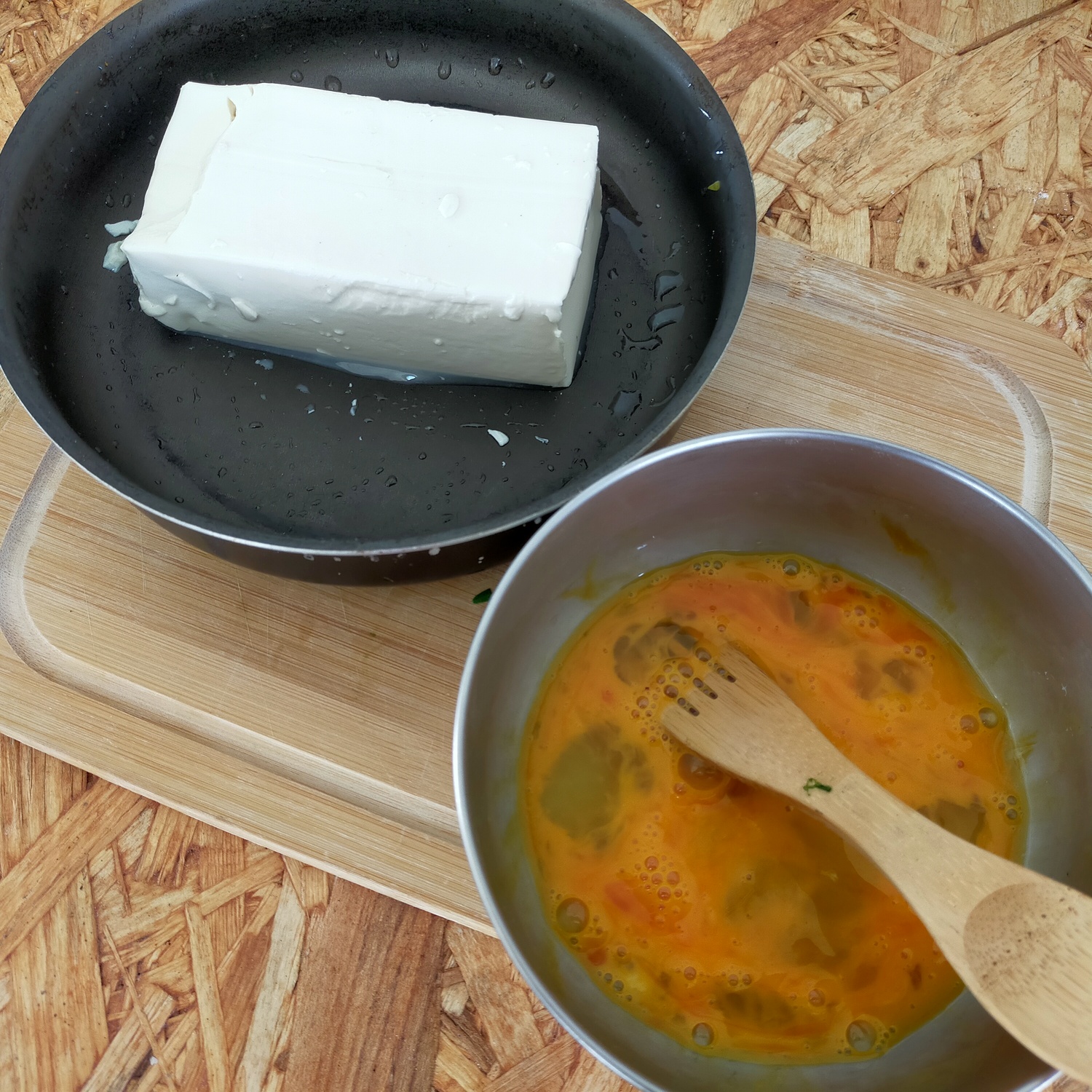 フライパンに入った豆腐とボウルに入った液状の生卵が並んでいる。