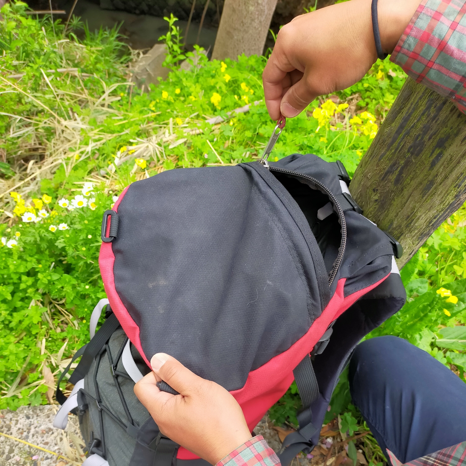 バックパックの上部にある雨蓋部分の収納のチャックを開けている。