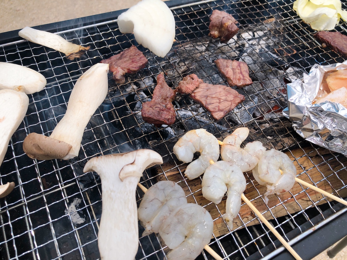 BBQコンロで肉やキノコを焼いている。