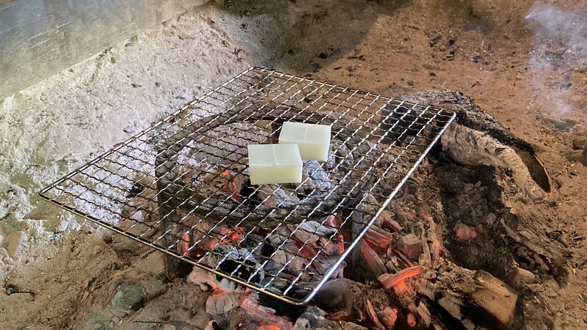 囲炉裏の網の上でお餅が二つ焼かれている。