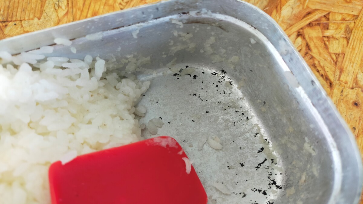炊飯した米が脇にどけられて、クッカーの底が見えている。底には焦げ付きは見られていない。