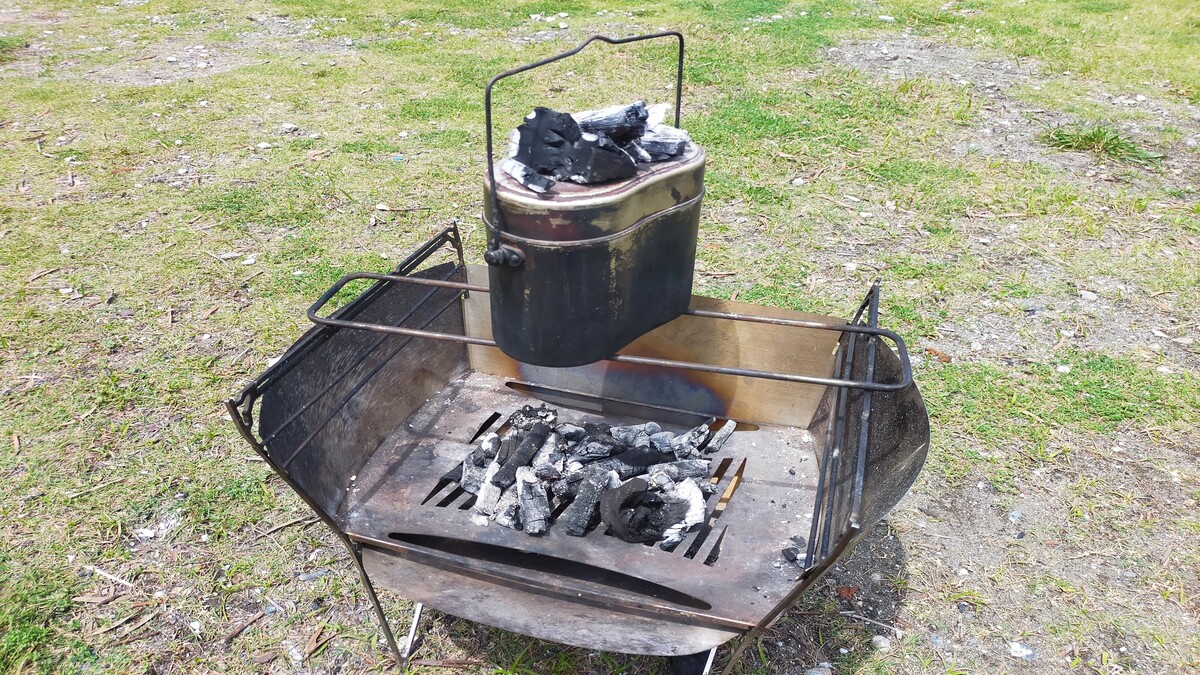 焚き火台の上に飯盒が置かれている様子。