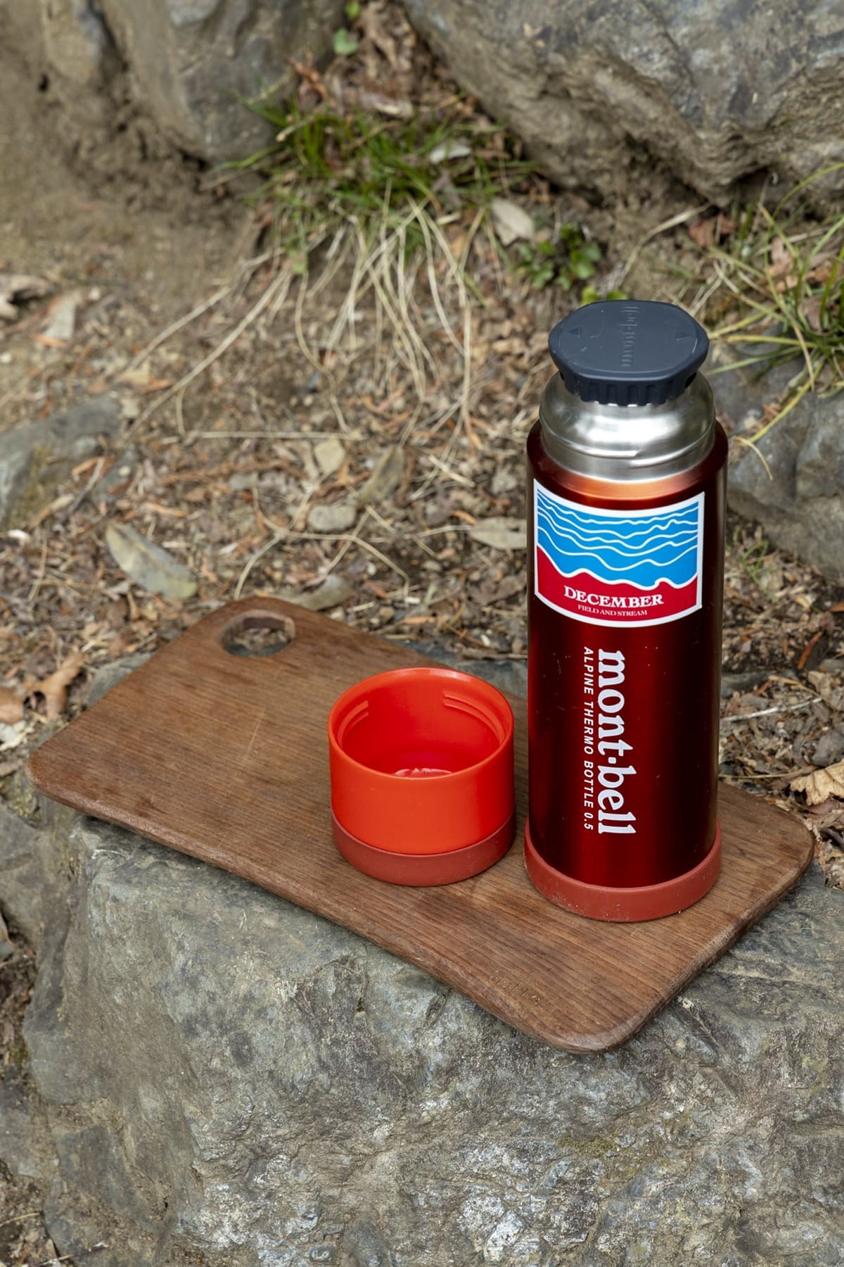 赤い保温水筒。岩の上の木のまな板の上に置いてある