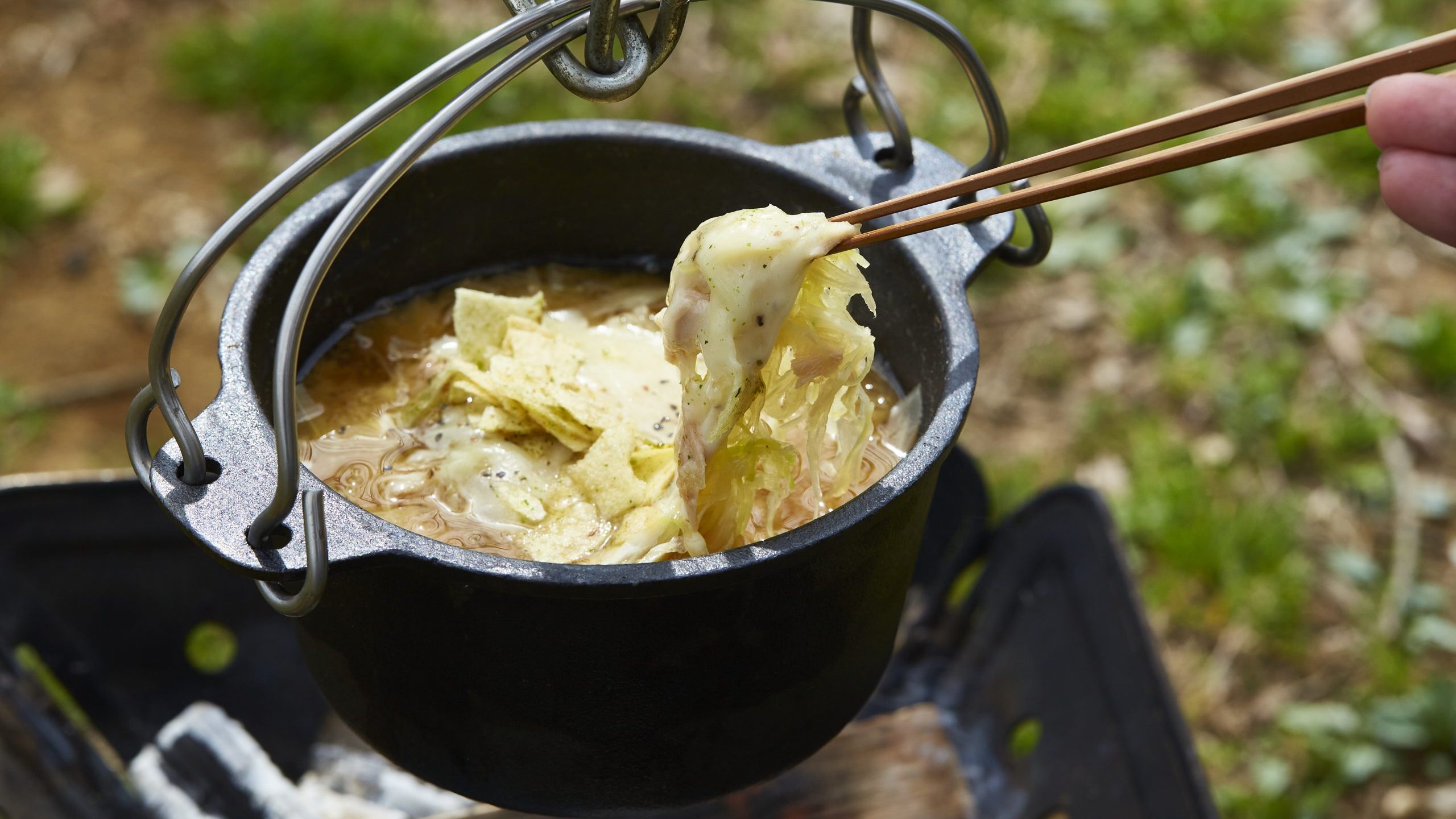 完成した料理を箸でつまんでいる。