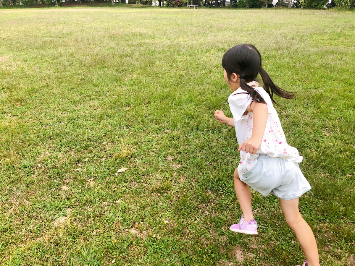 芝生を走る少女の後ろ姿