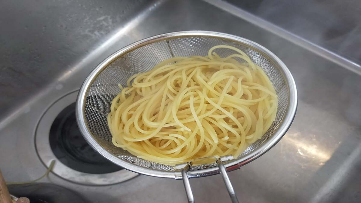 ざるを使って、茹でたパスタのお湯を切っている様子。