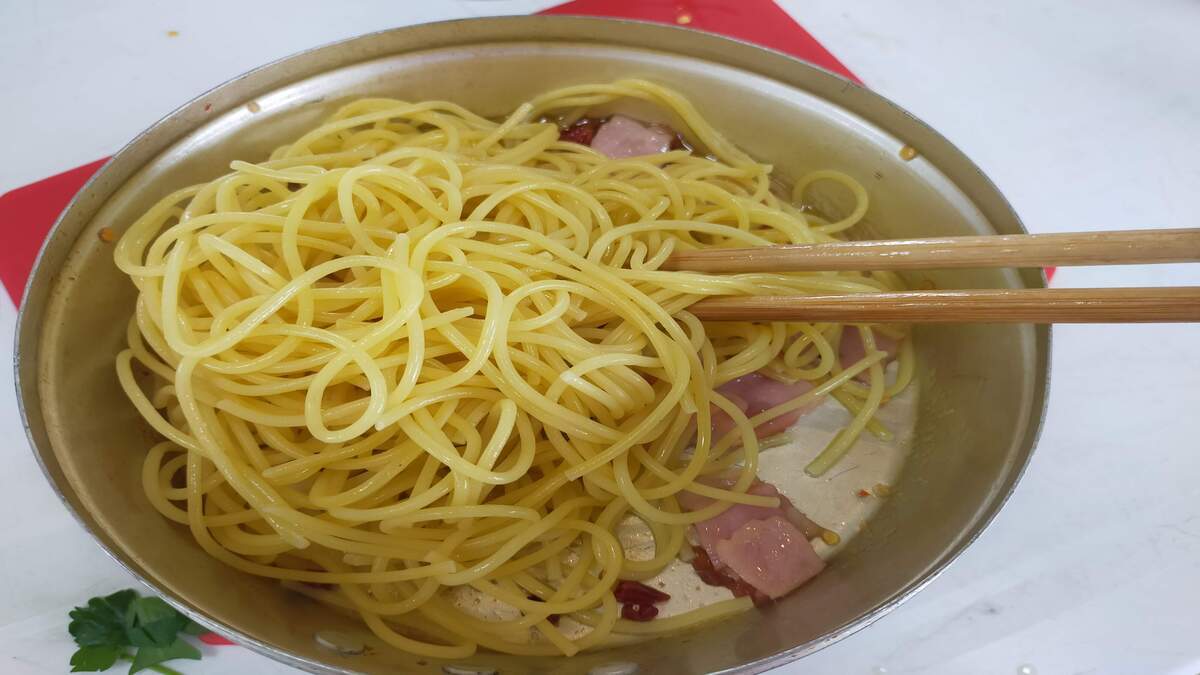 フライパンに入ったパスタを菜箸でかき混ぜている。