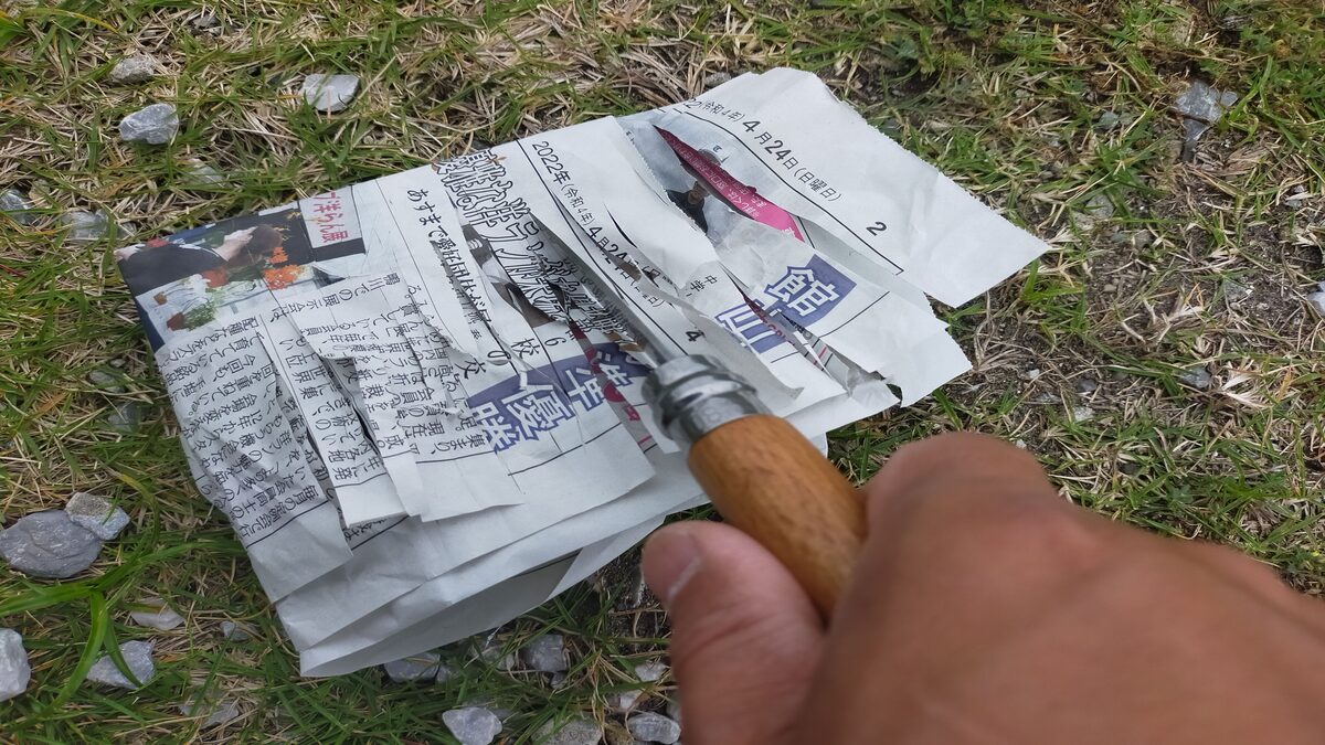 新聞紙でナイフの切れ味を確認している。新聞紙にたくさんの切れ込みがある。