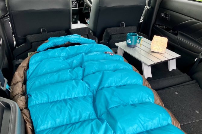 車のラゲッジスペースに寝袋とテーブルを設置している