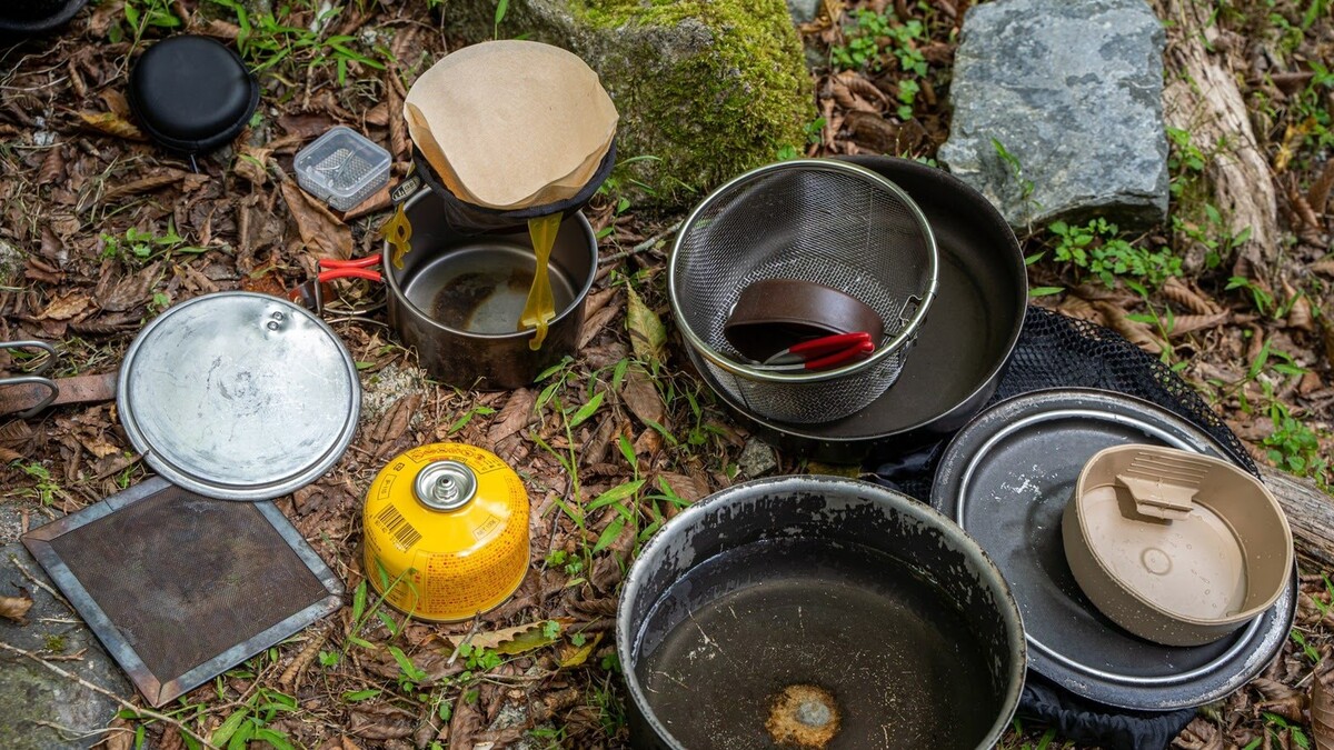 クッカーやフライパンなどの調理器具が地面に並んでいる様子。