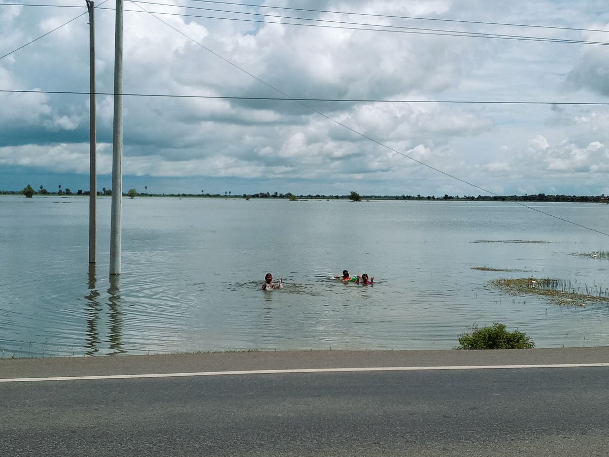 水没した田畑で浮き輪で遊ぶ子供たち