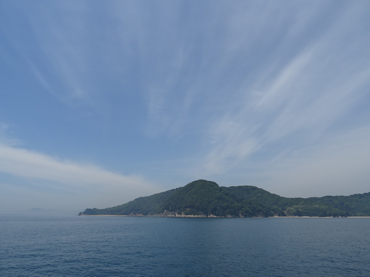 青い穏やかな海と青空の間に浮かぶ佐島