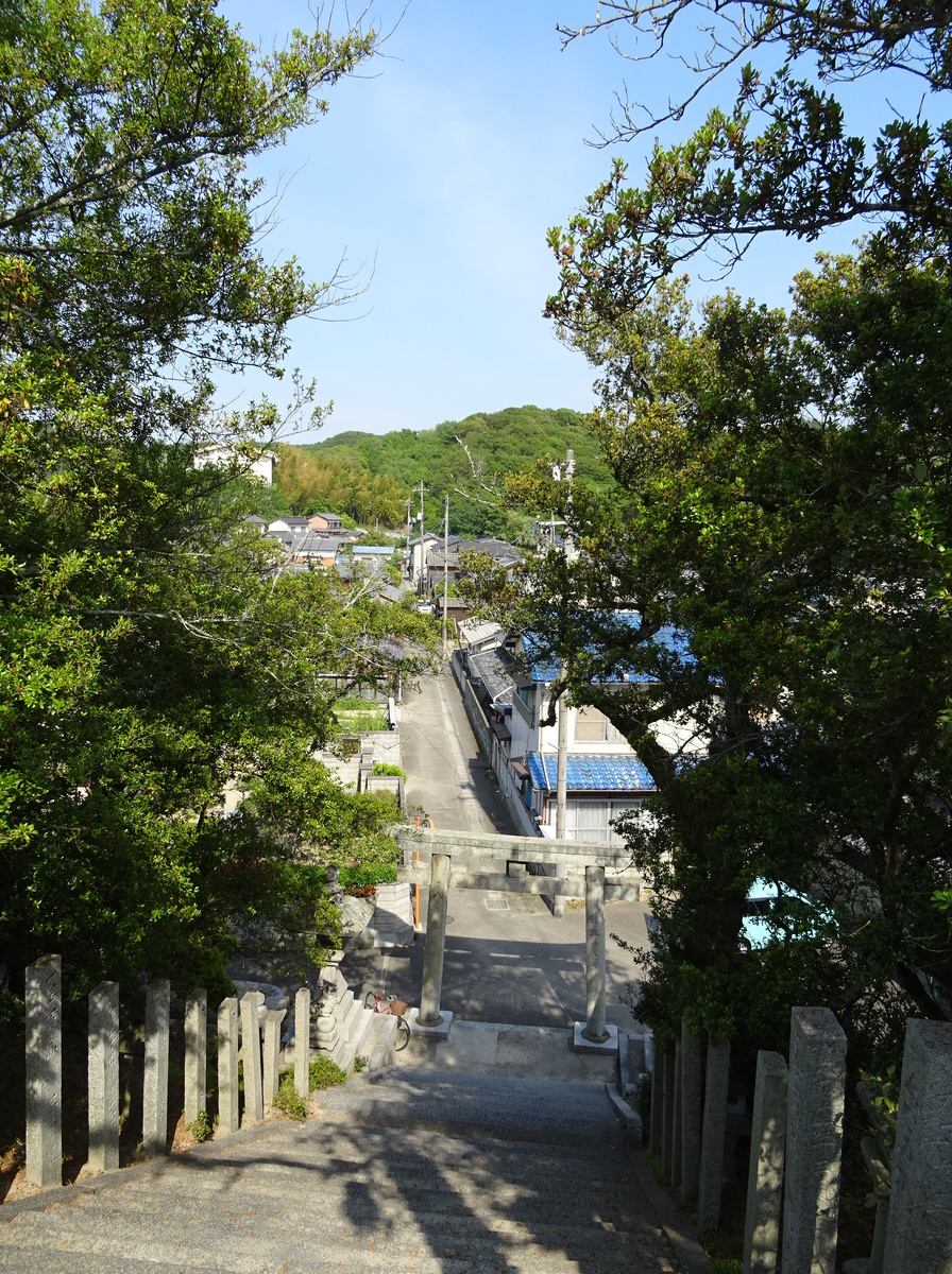 長い石段の下に石の鳥居。その向こうにまっすぐの道が続く