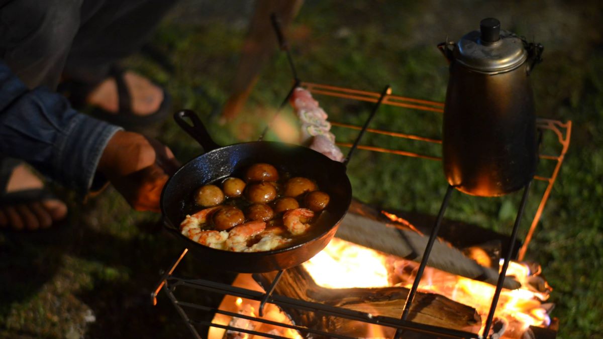 焚き火台の上にスキレットを乗せて調理している様子。