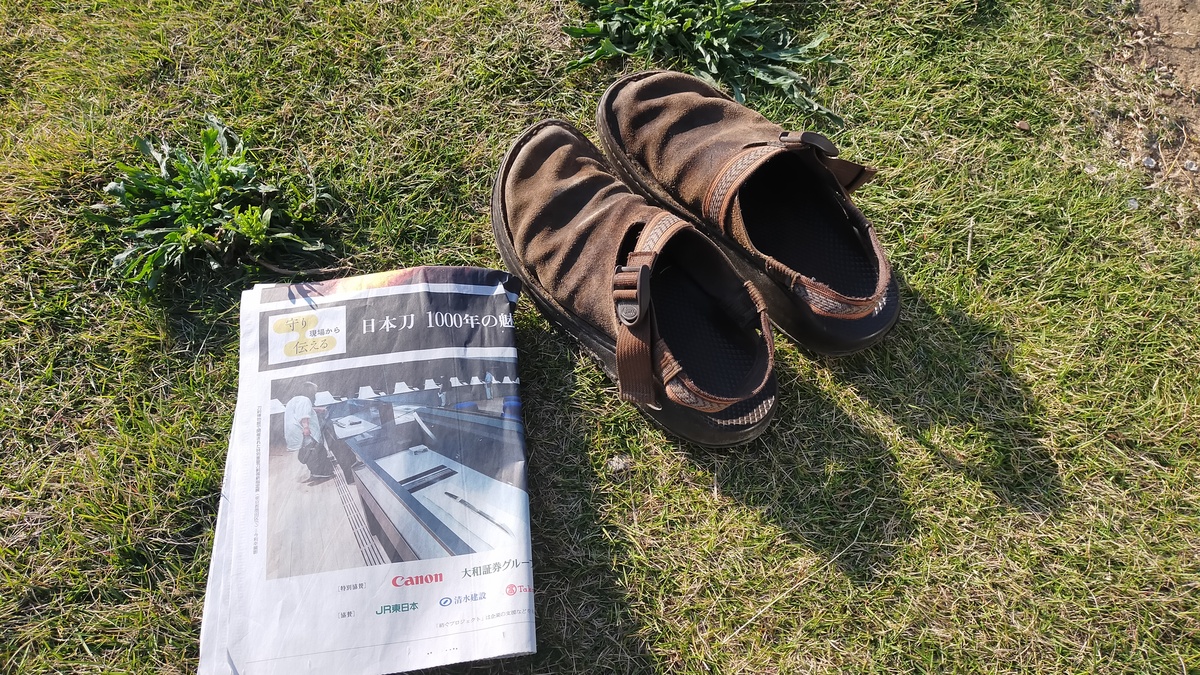 靴と新聞紙が地面に置かれている。