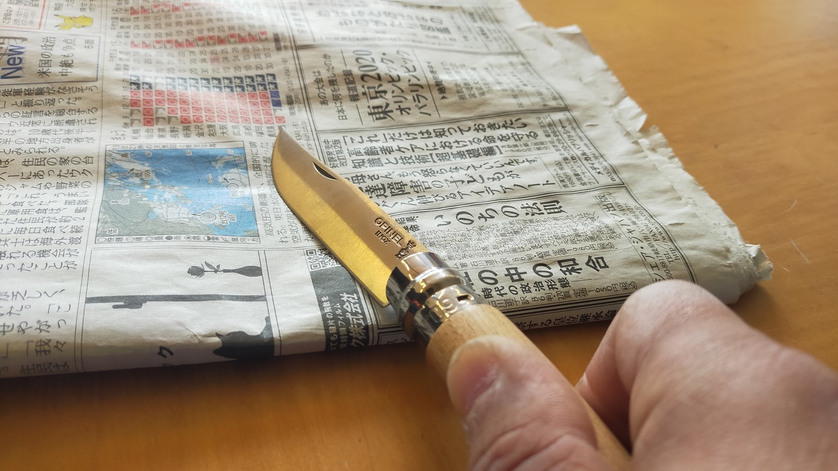 新聞紙の上でナイフを擦っている様子。