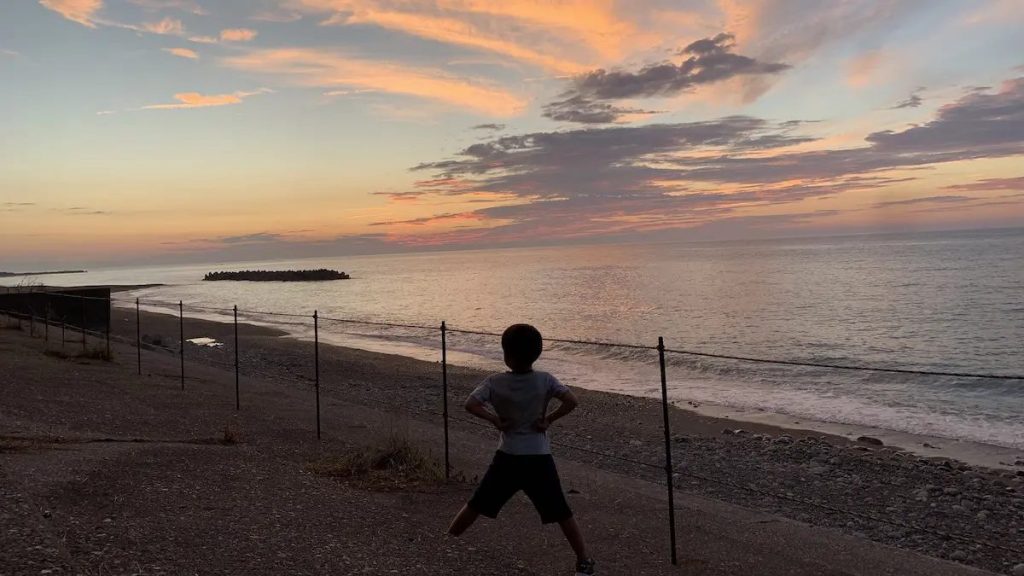 海の前でポーズをとる男の子