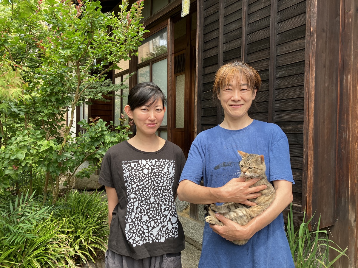 左側に黒いTシャツを着た黒髪のケイコさん。右側に青いTシャツを着て猫を抱っこしている美絵さん。