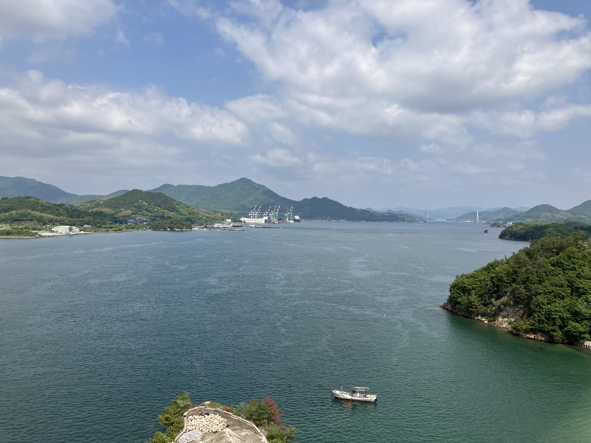 島から見た海の景色。近隣の島々も見える。手前に小さな漁船が一隻浮かんでいる。