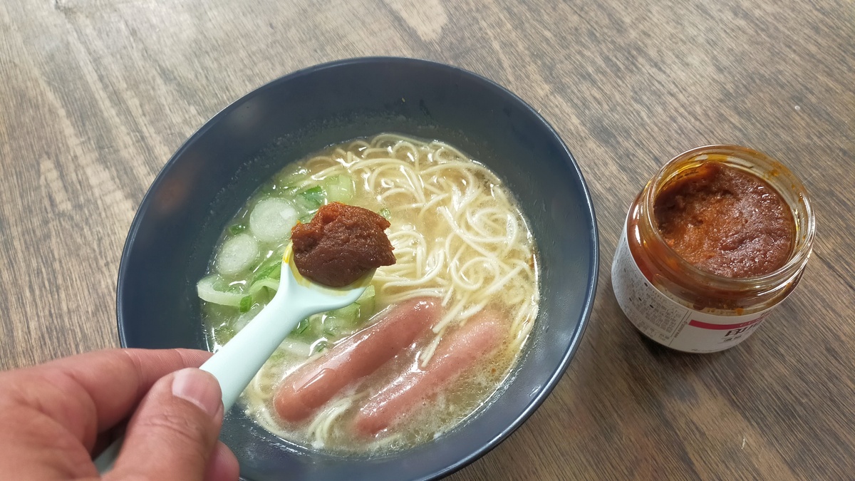 ラーメンの中にカレーペーストを入れようとしている様子。