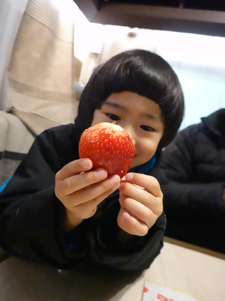 トレーラー内で苺を食べる子ども