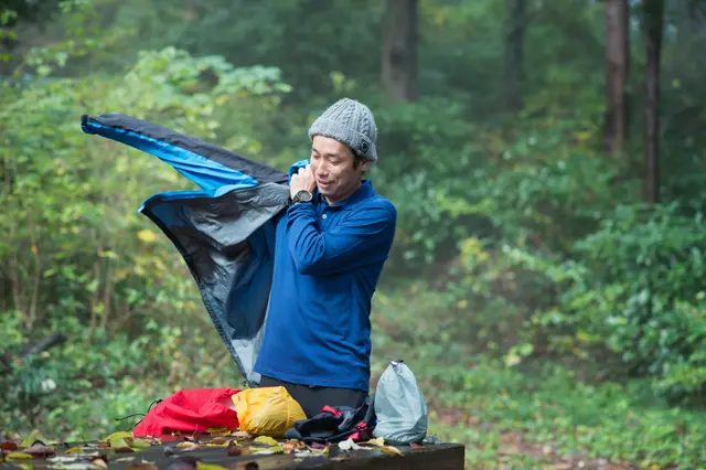 屋外でアウターを着る男性