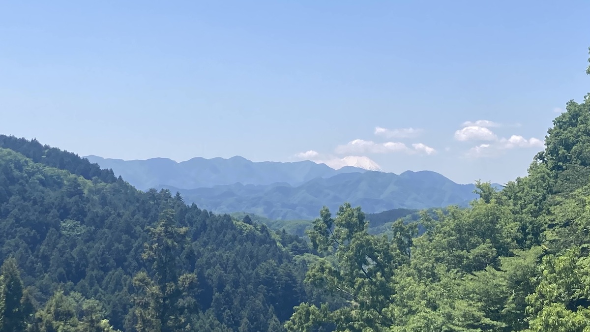山々の間から遠くに富士山がそびえている。