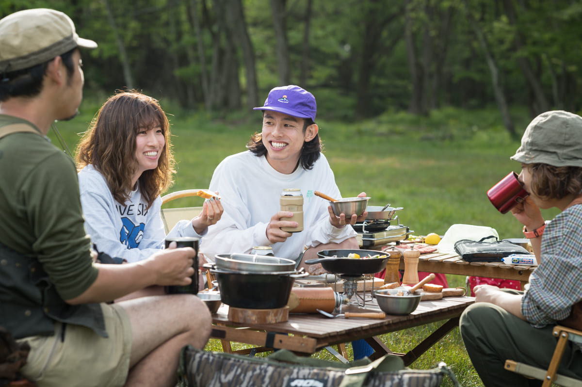 キャンプ料理を食べながら談笑する4人