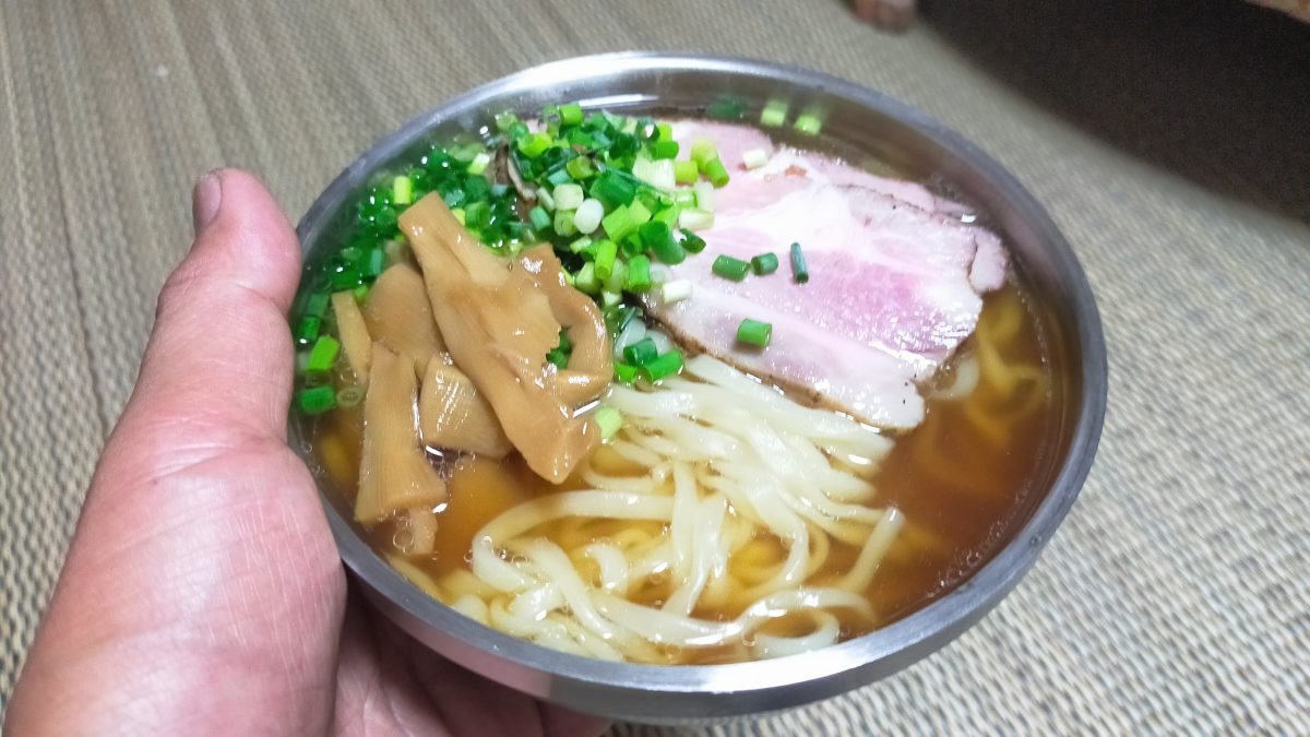 ラーメンをよそった2重ステンレス茶碗を手で持っている様子。