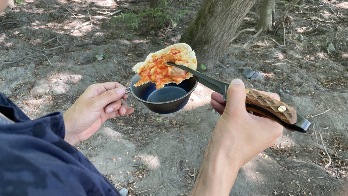 トングでピザを食べている様子