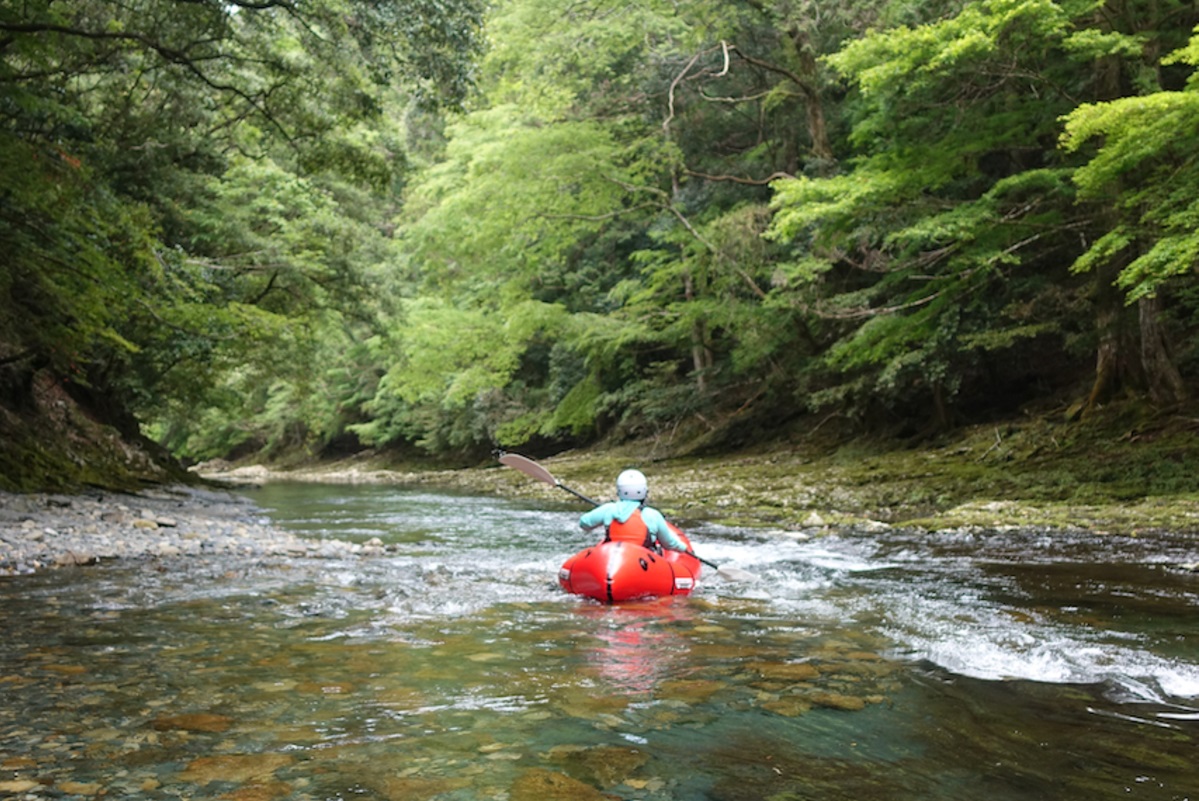 川の流れにのってパックラフトを漕ぐ女性