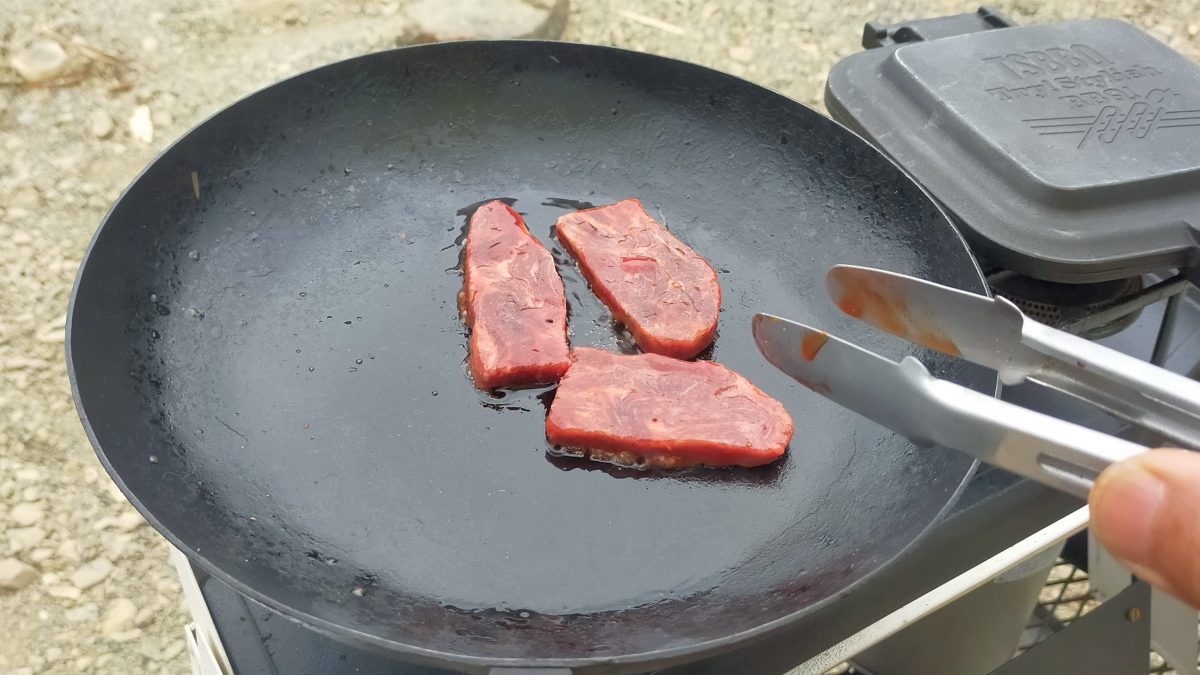 フライパンで肉を焼いている。