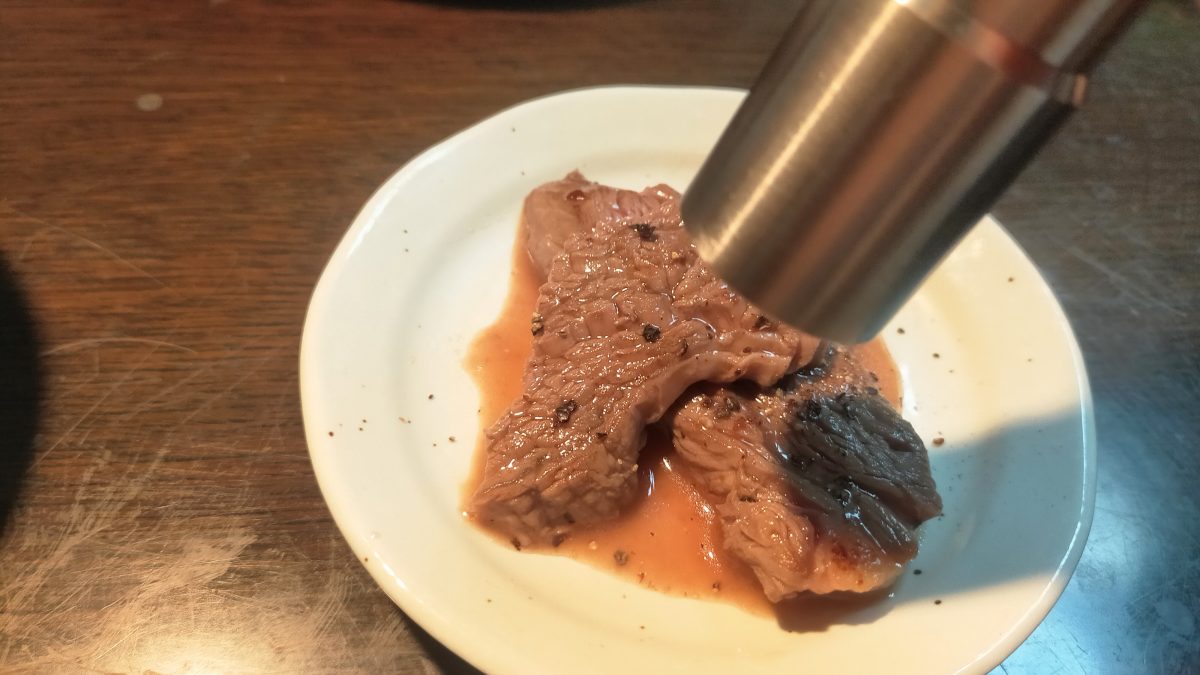 肉の上にコショウを挽いてかけている様子。