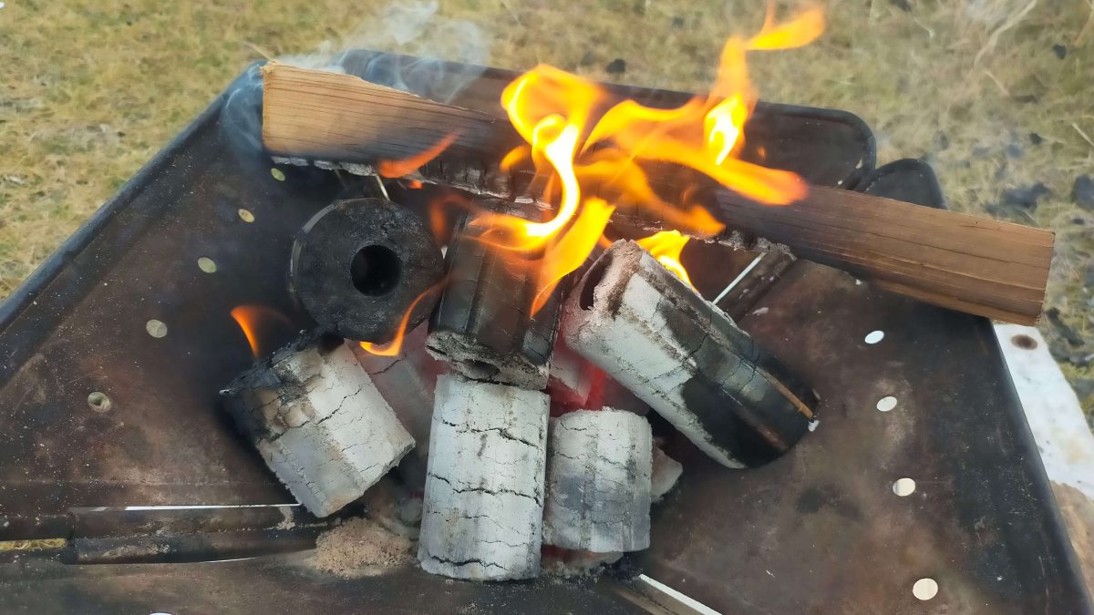 焚き火台の上でモミガライトと薪が燃えている様子。
