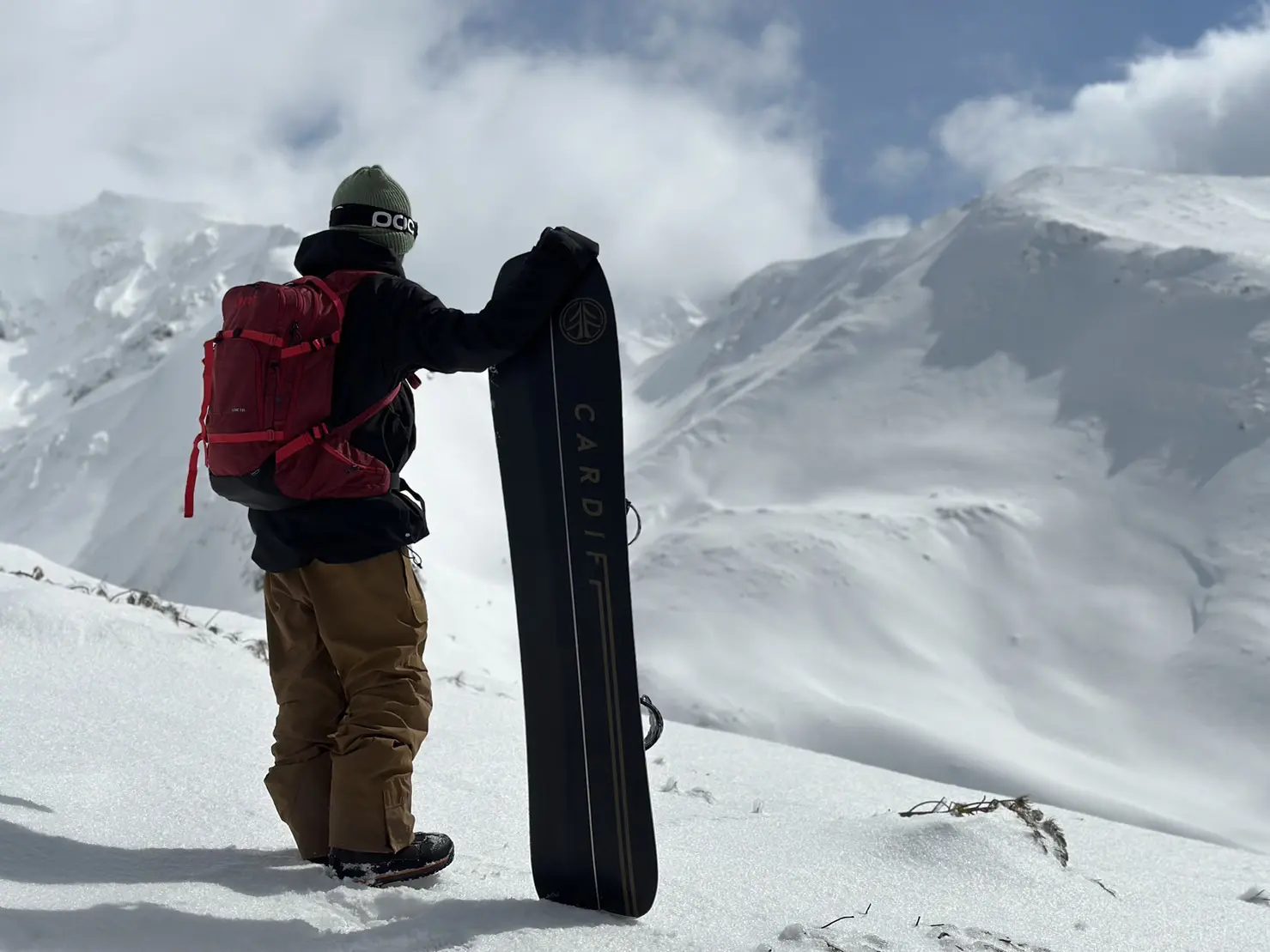 雪山を見つめるスプリットボードを持った人物